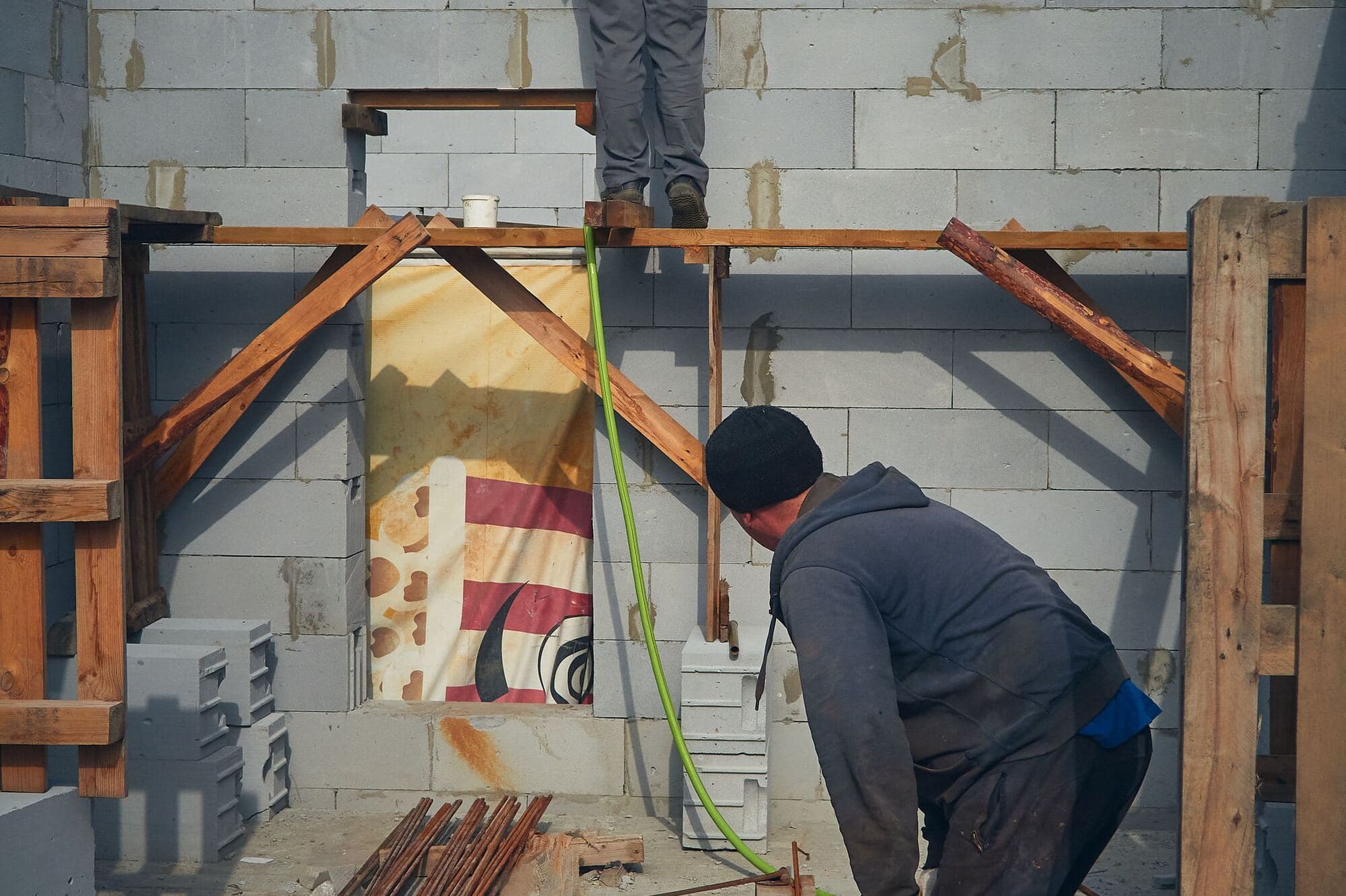 Two workers laying up a block wall on a job site