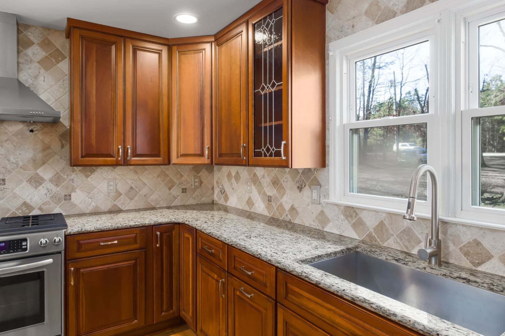 Remodeled kitchen with wood cabinets, granite counters and a tile backsplash